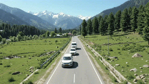 Cars travelling through a green Kashmir mountain valley
